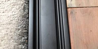 A black door with some wood on the floor