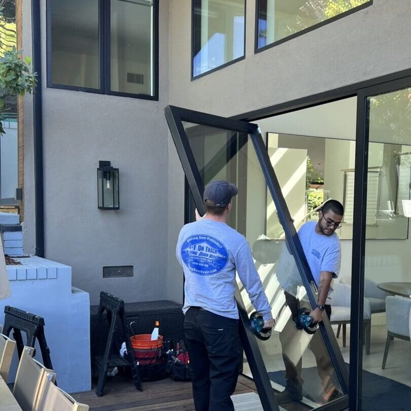 Two men are working on a patio door.